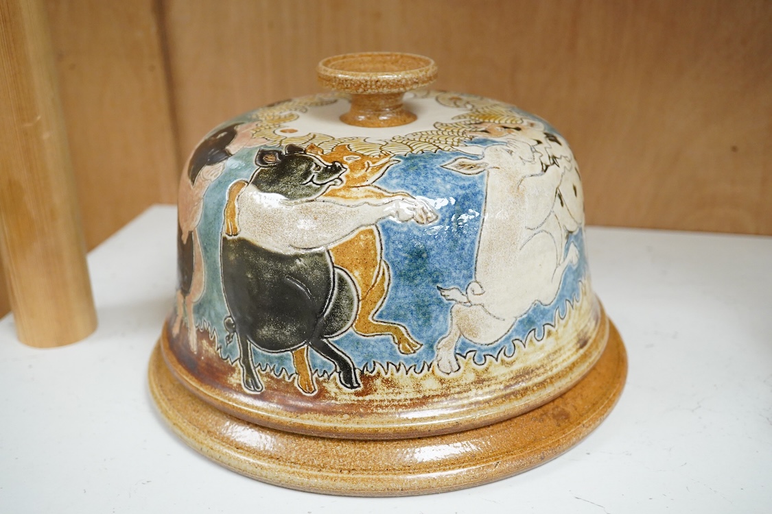 A Michael Mosse Llanbrynmair Pottery cheese dish and cover, incised and painted with dancing pigs, impressed marks, dish 23cm diameter.